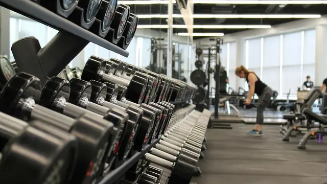 Mujer entrenando en un gimnasio con mancuernas