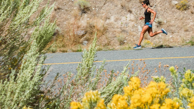 Mujer corriendo por una carretera en un día soleado