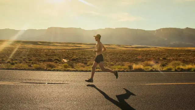 Hombre corriendo por una carretera al atardecer