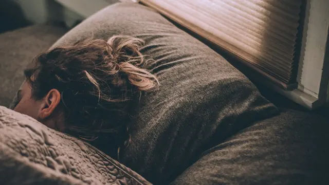 Mujer durmiendo en la cama bajo una manta