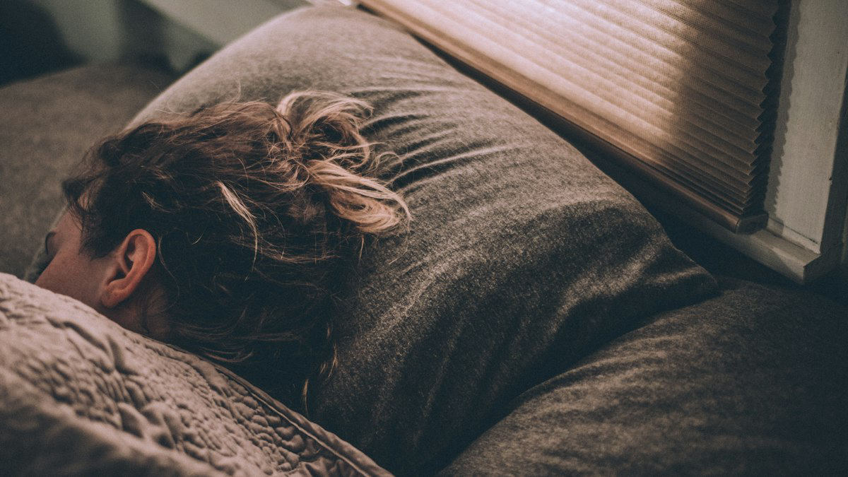 Mujer durmiendo en la cama bajo una manta