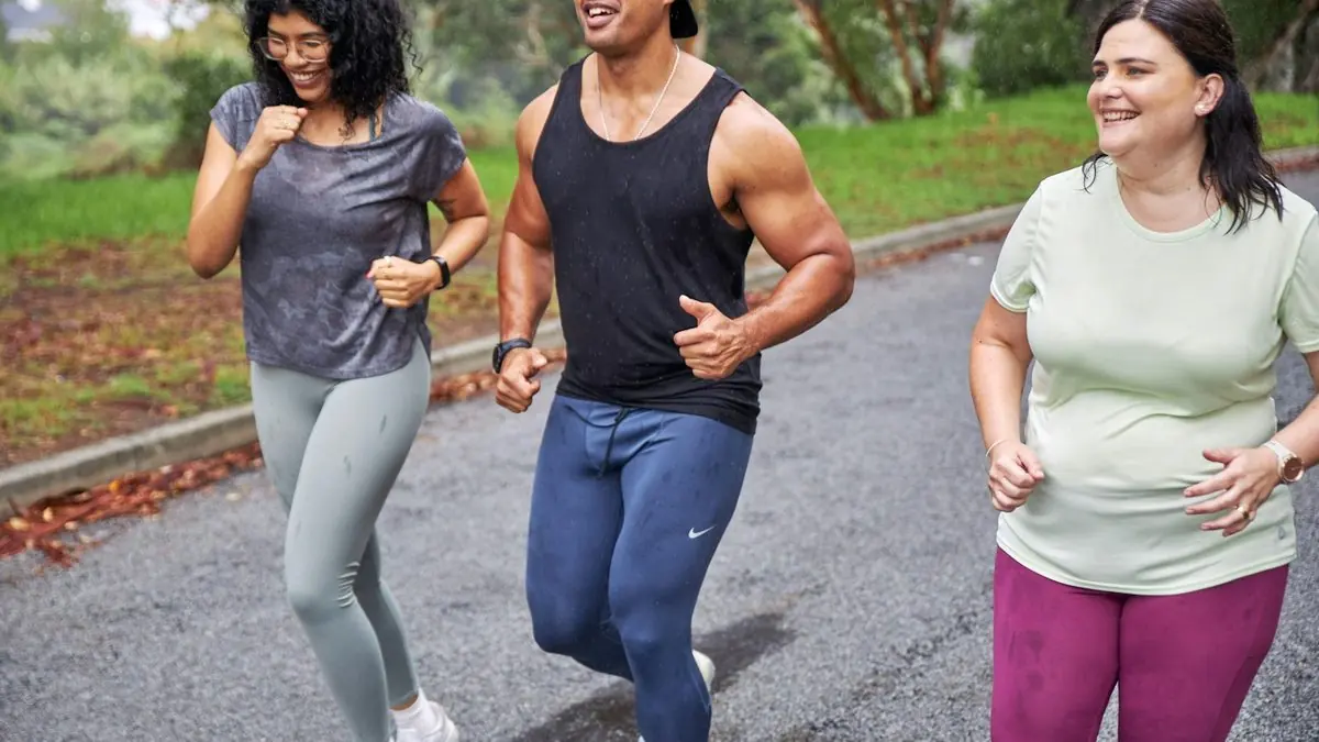 Tres amigos corriendo juntos por un camino, sonriendo