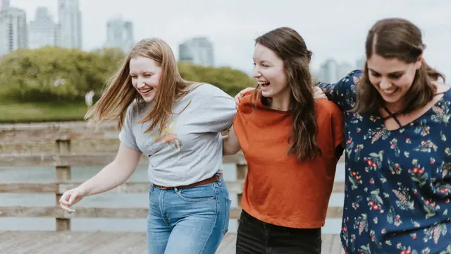 Tres amigas paseando y riendo junto al agua