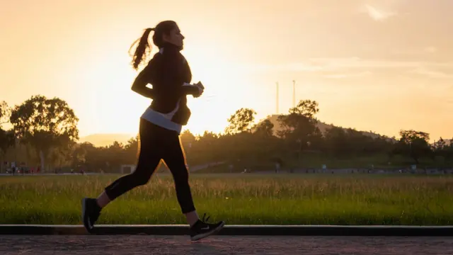 Mujer corriendo por un camino al atardecer