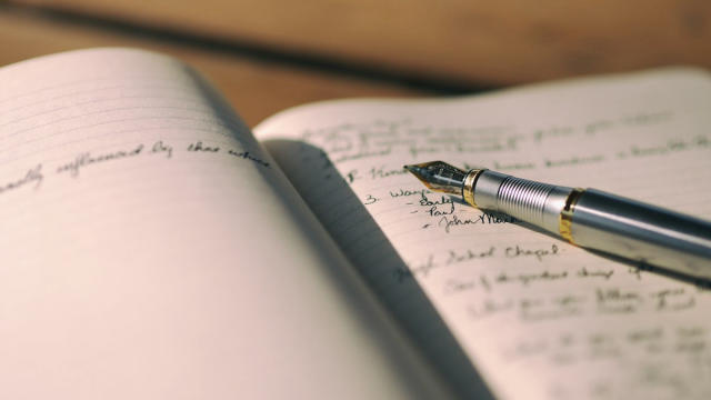 Pluma sobre una libreta con texto escrito a mano