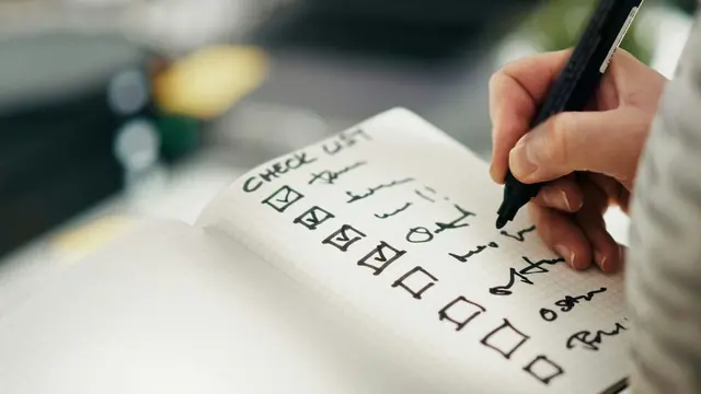 Mano marcando las casillas de una lista en un cuaderno