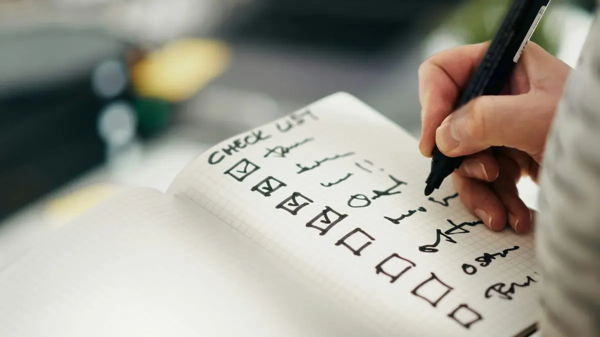 Mano marcando las casillas de una lista en un cuaderno