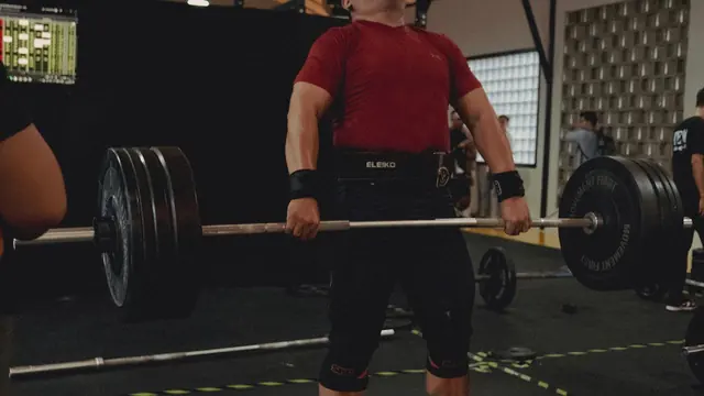 Hombre haciendo peso muerto con barra en el gimnasio